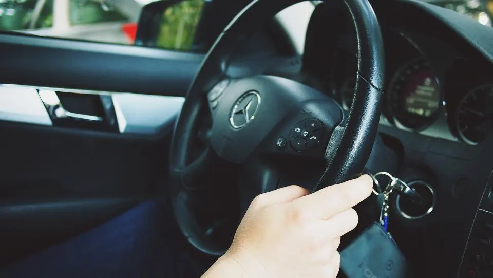 Mão ao volante de um carro, com as chaves na ignição